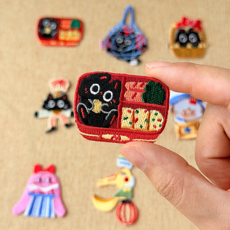 Majiang patches, with the Bento Box patch held between two fingers to show its size