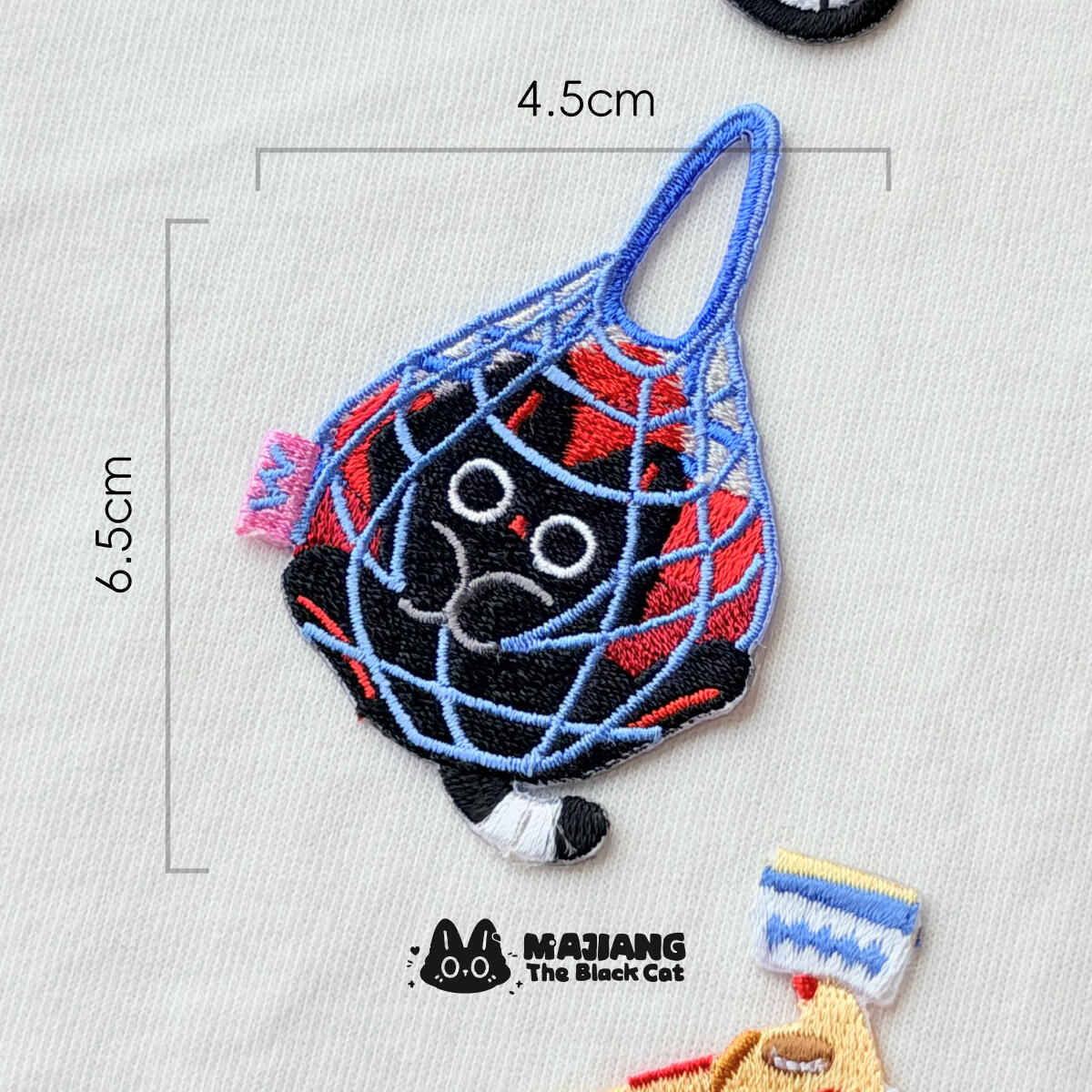 Net Bag patch: Majiang squished into a blue string bag, 45 × 65 mm